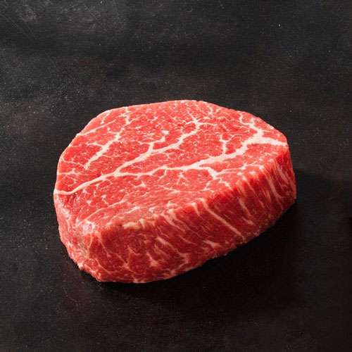 Bít tết Wagyu sống nằm trên thớt đá cẩm thạch với một chai Legent Bourbon và ly rượu bourbon đặt phía sau